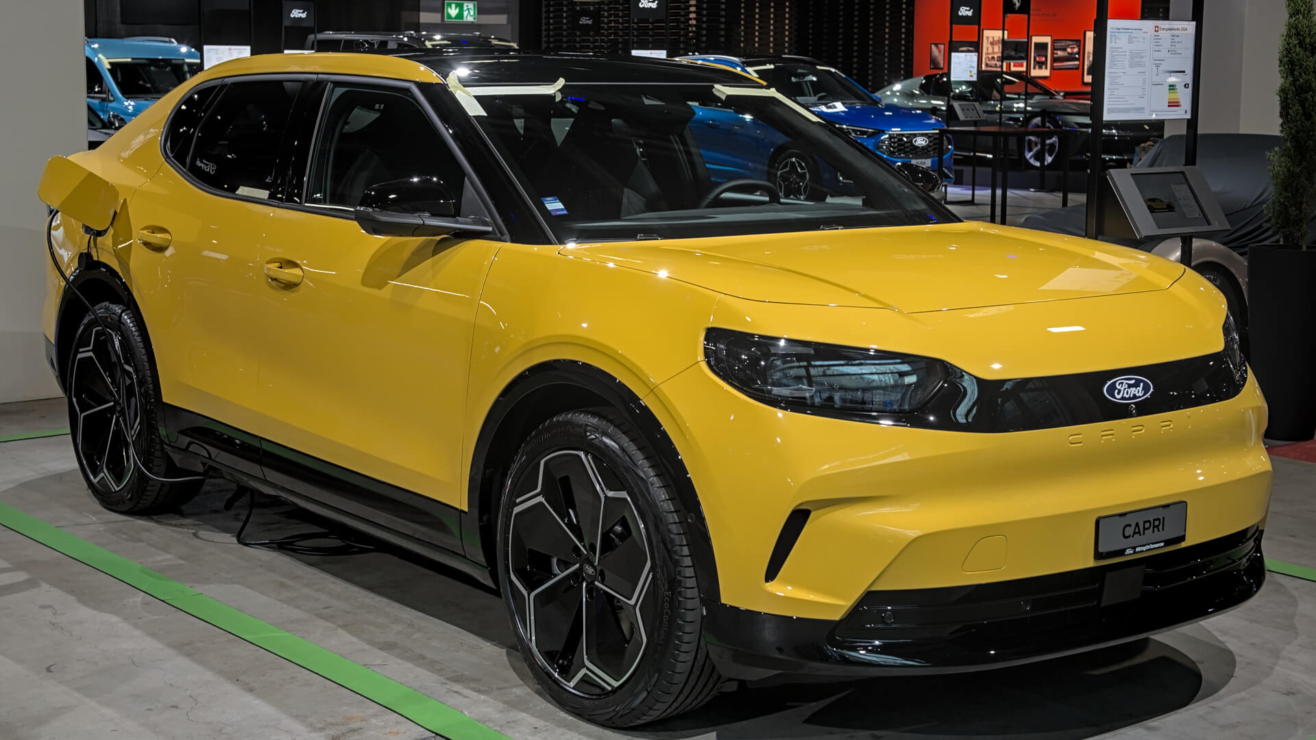 Photo of a yellow Ford Capri EV on charge at a trade show.