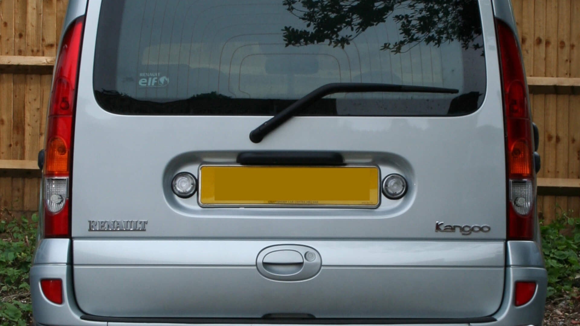 Photo of a silver Renault Kangoo van parked in front of a wooden fence