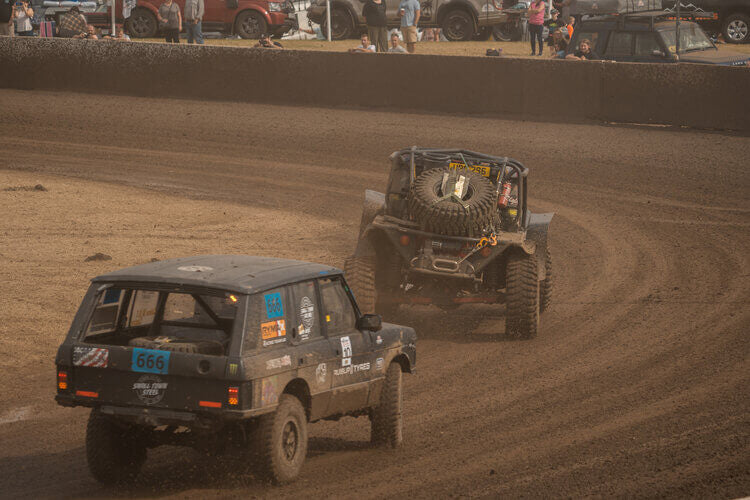 Photo of 2 off-road vehicles on a dirt rally track.