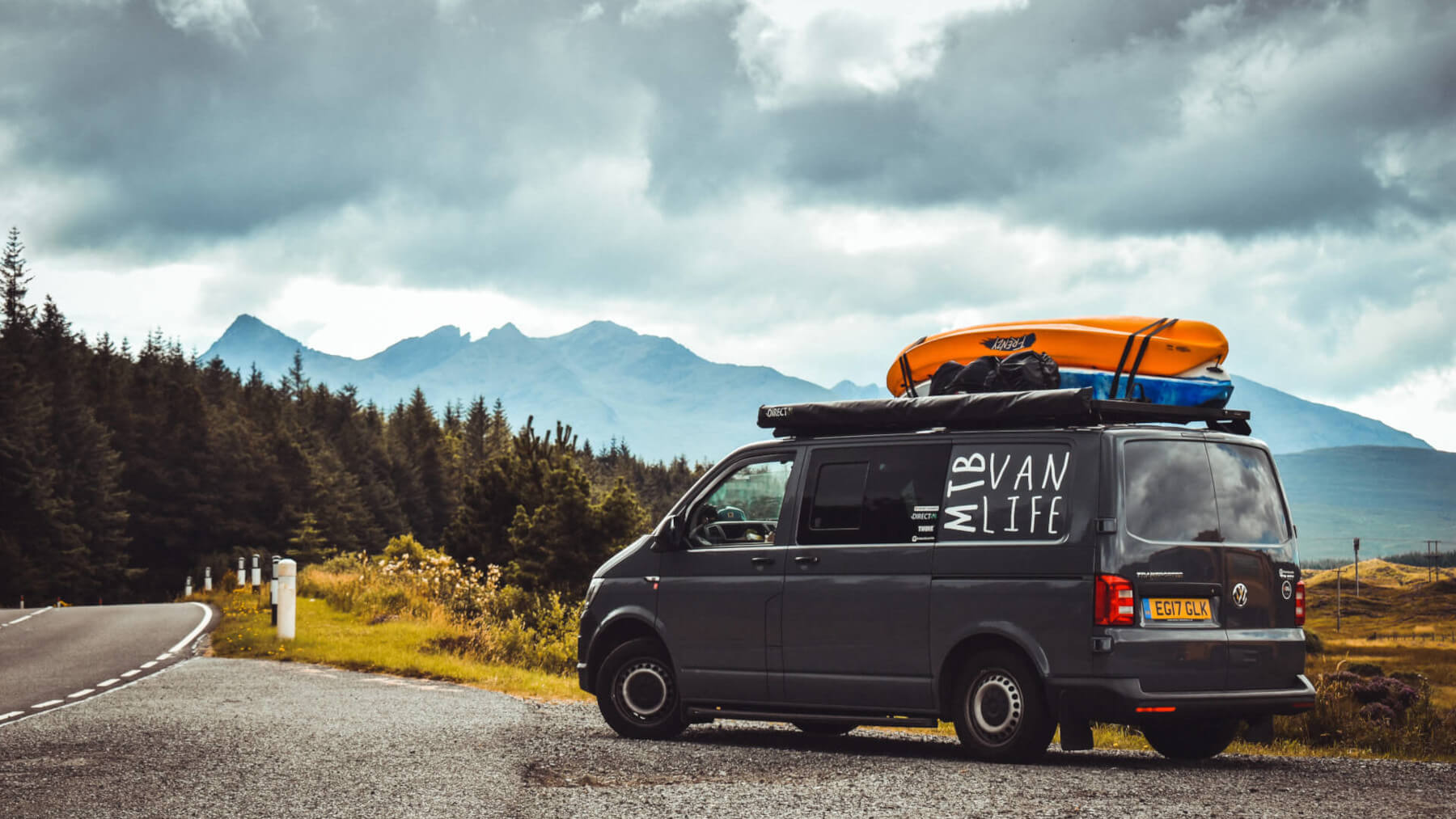 Volkswagen Transporter T5 from MTB Van Life kitted out with expedition accessories from Direct4x4 in a layby on a country road with trees and mountains in the background