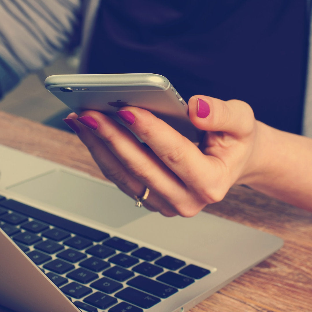 Direct4x4 finance options with person holding phone in front of a laptop on a wooden desk