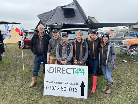 Photo of the Direct4x4 team stood in front of a Land Rover Defender in a field.