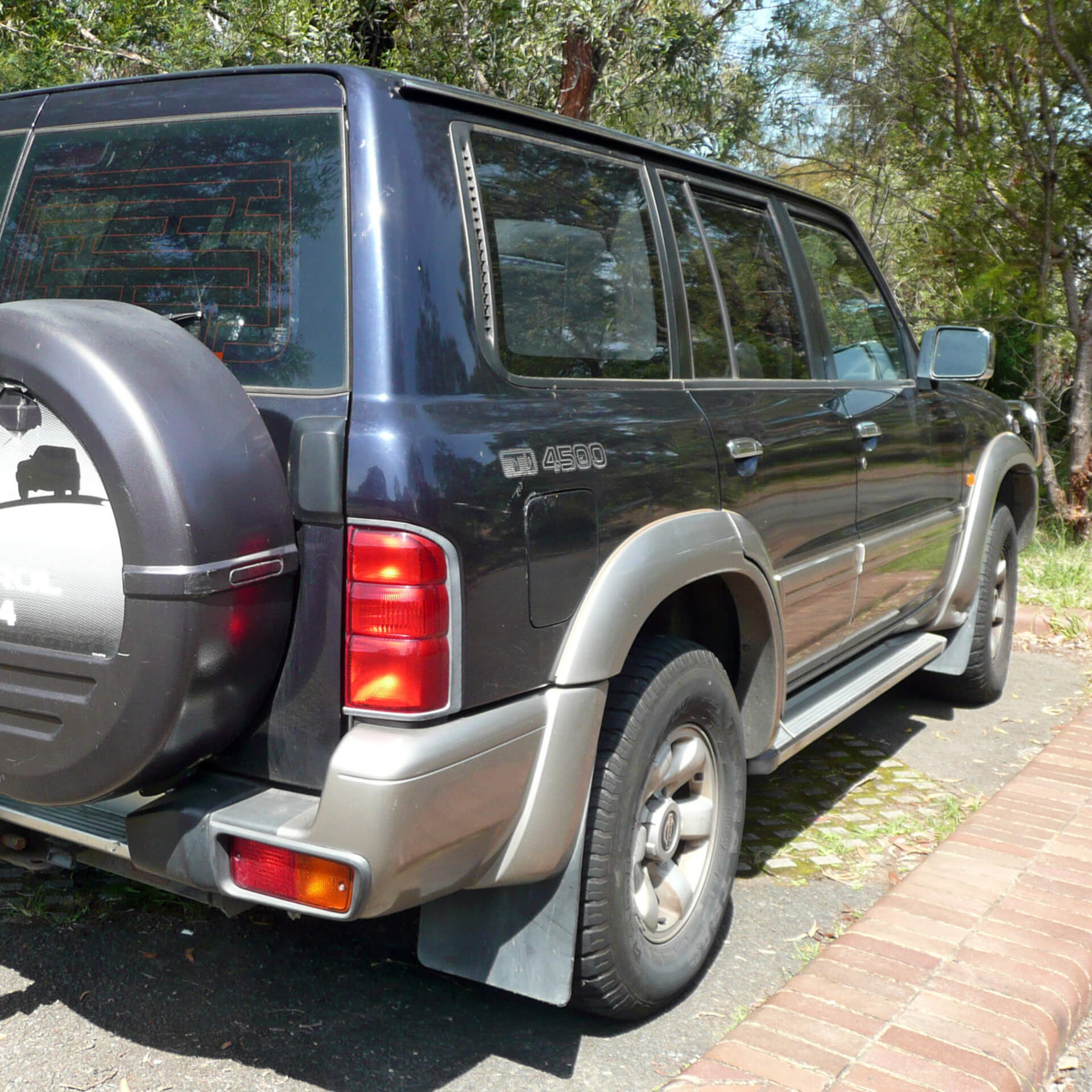 Direct4x4 accessories for Nissan Patrol vehicles with a photo of a Nissan Patrol from the rear parked on a driveway in front of trees