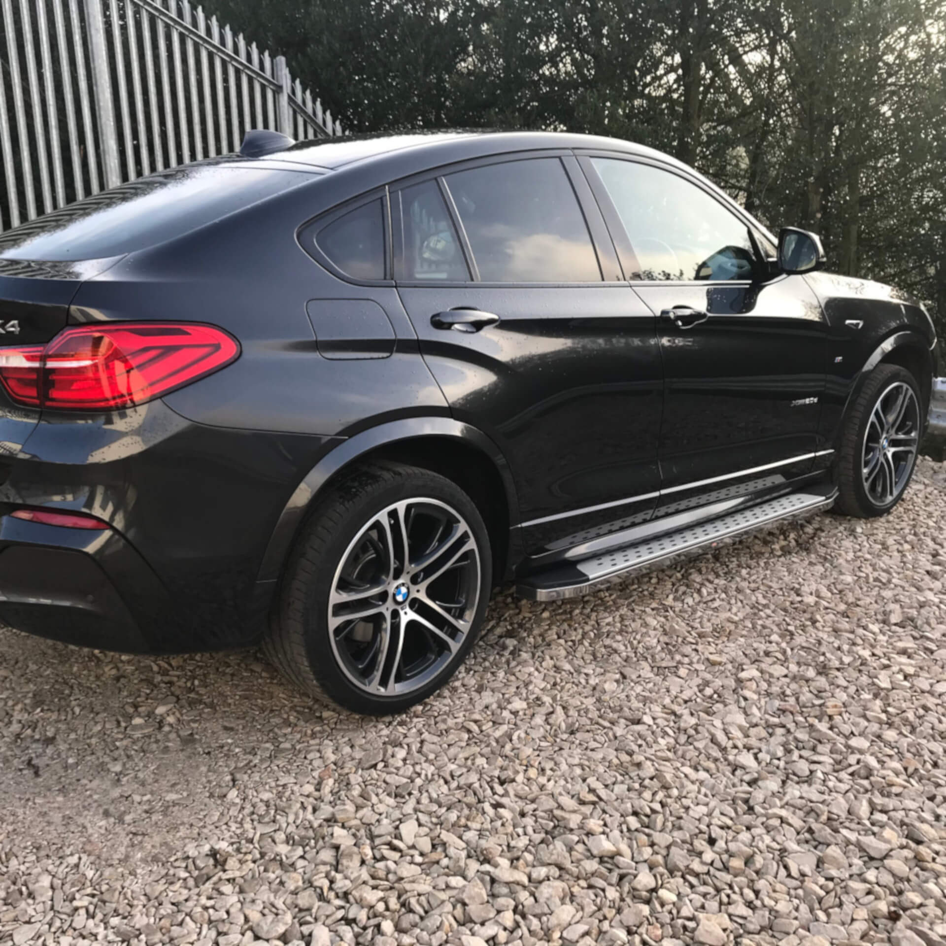 Direct4x4 accessories for BMW X4 vehicles with a photo of freedom side steps fitted to a black BMW X4 parked on gravel