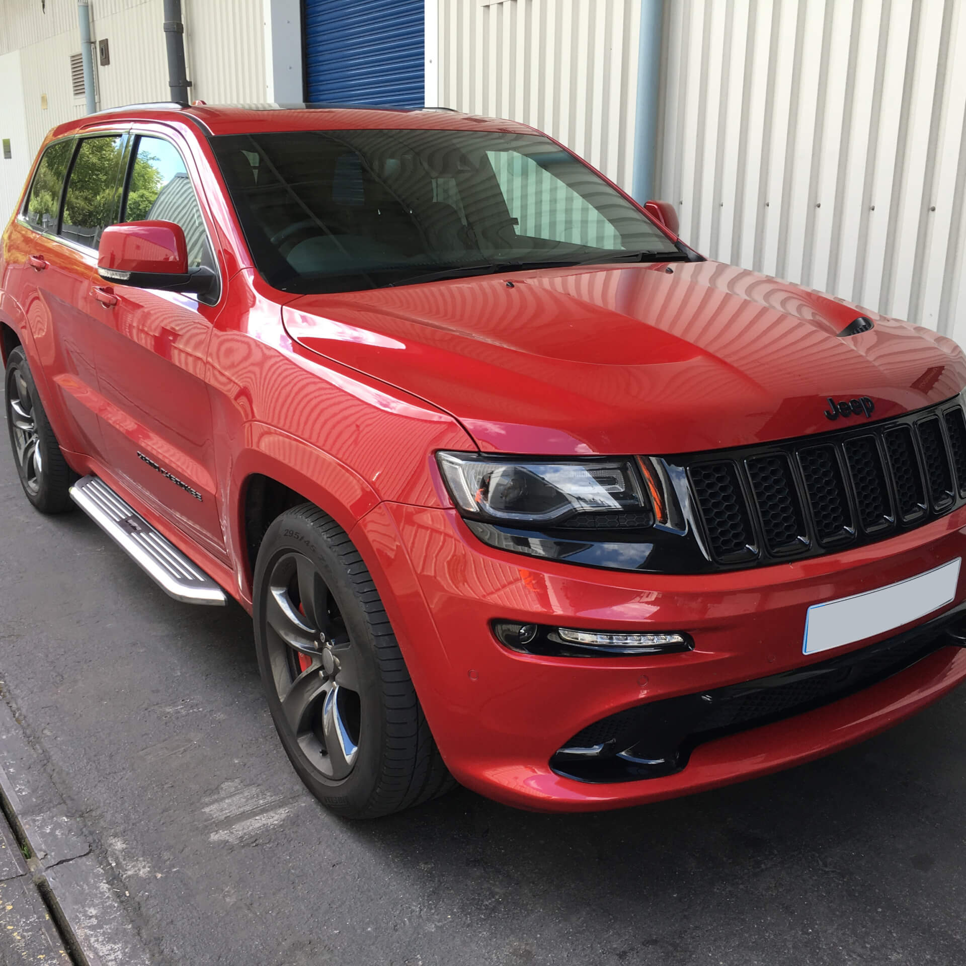 Direct4x4 accessories for Jeep Grand Cherokee vehicles with a photo of a red and black Jeep Grand Cherokee outside our depot fitted with our premier side steps