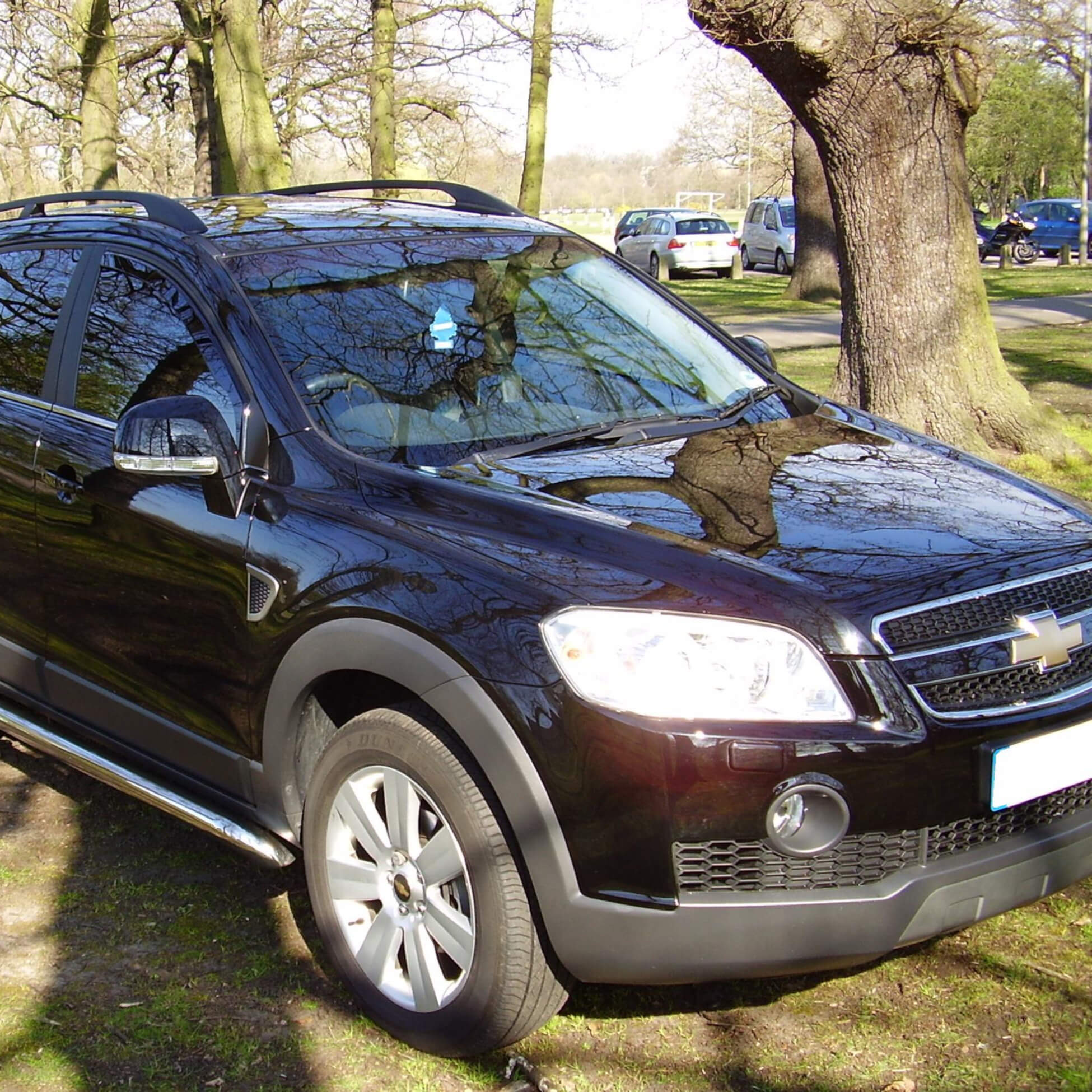 Direct4x4 accessories for Chevrolet Captiva vehicles with a photo of a black Chevrolet Captiva parked in front of trees in the sunlight