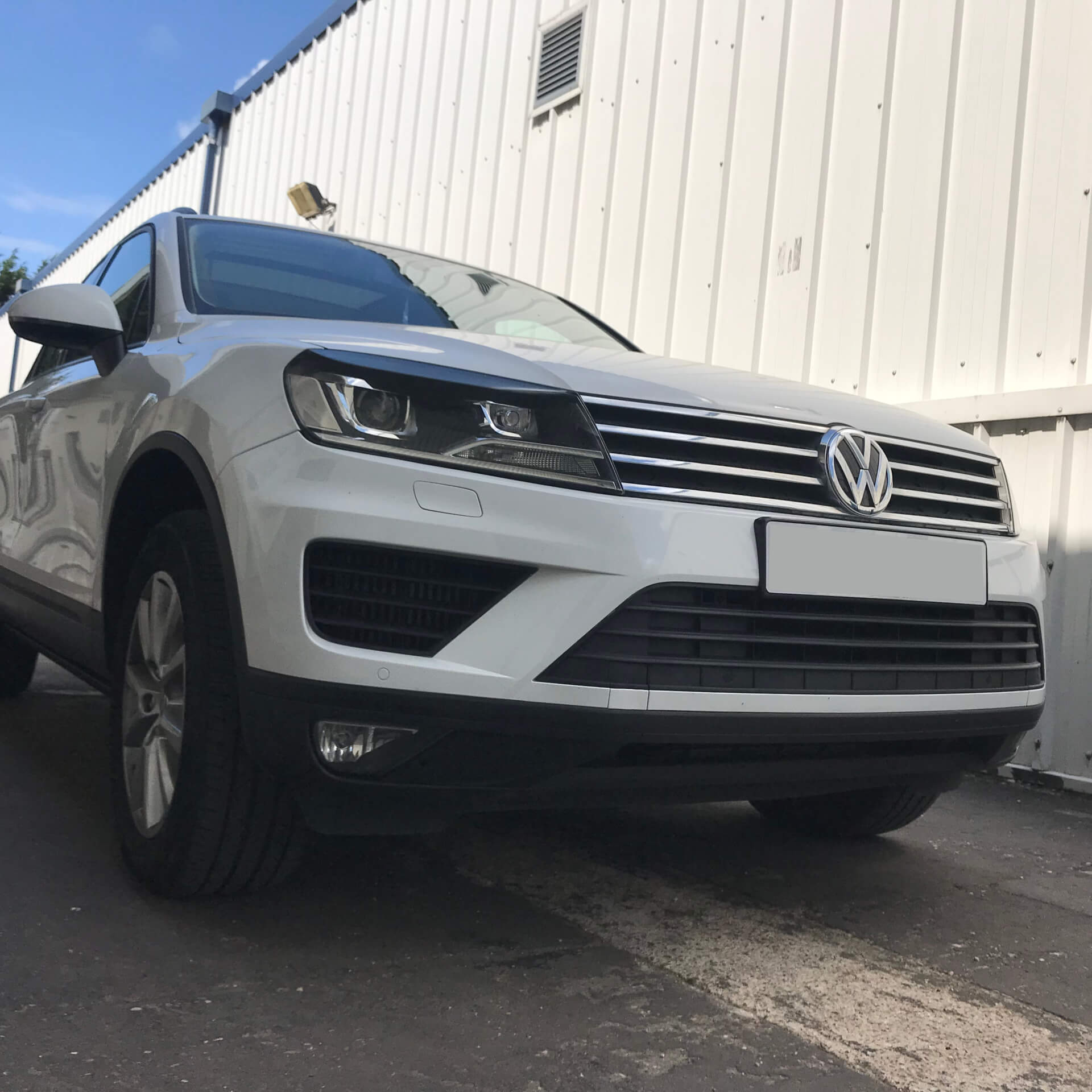 Direct4x4 accessories for Volkswagen Touareg vehicles with a photo of the front of a white volkswagen touareg outside our offices with blue sky above