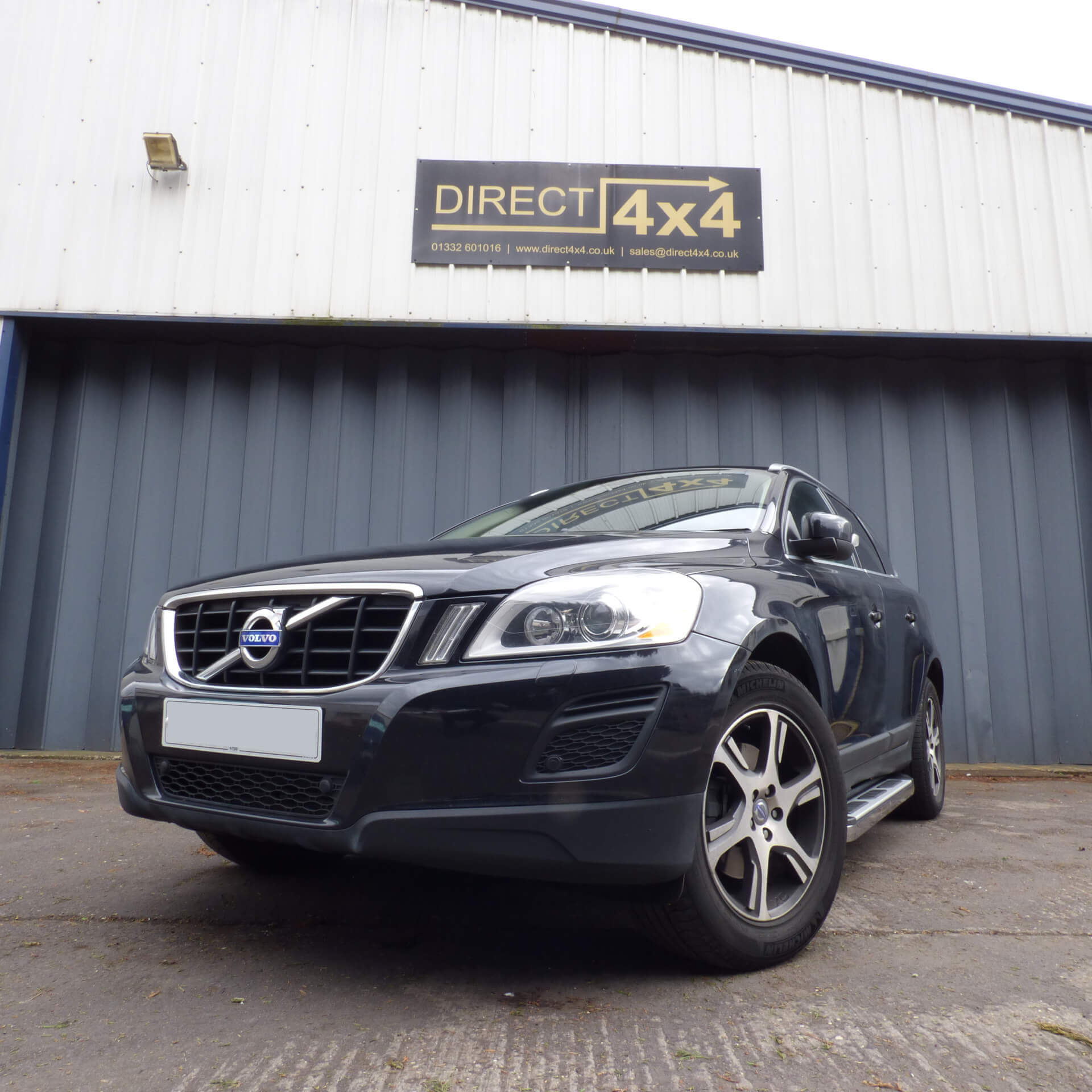 Direct4x4 accessories for Volvo XC60 vehicles with a photo of a black volvo xc60 parked under our direct4x4 sign outside our offices