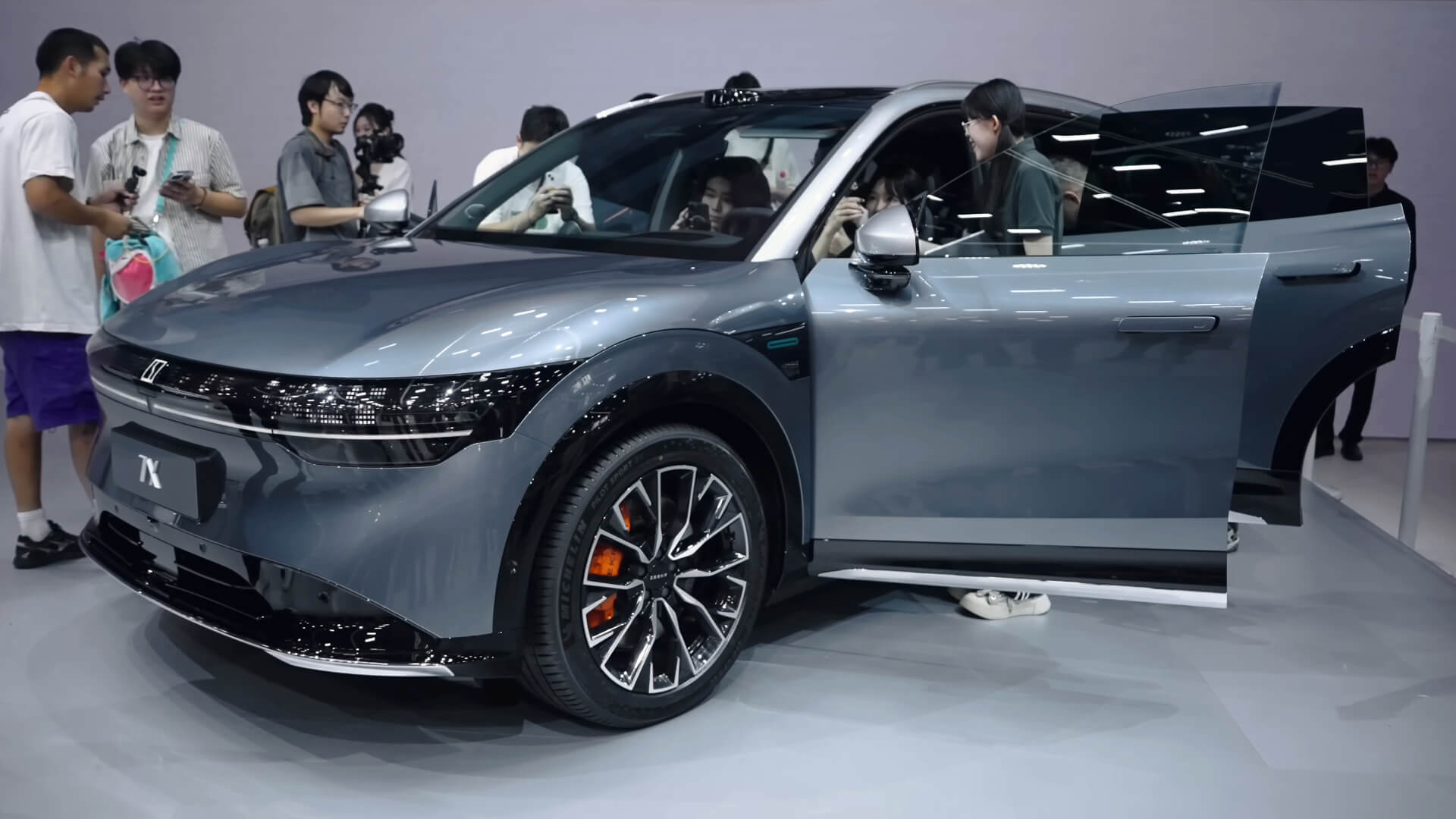 Photo of a silver coloured Zeekr 7X vehicle at a motor show surrounded by people