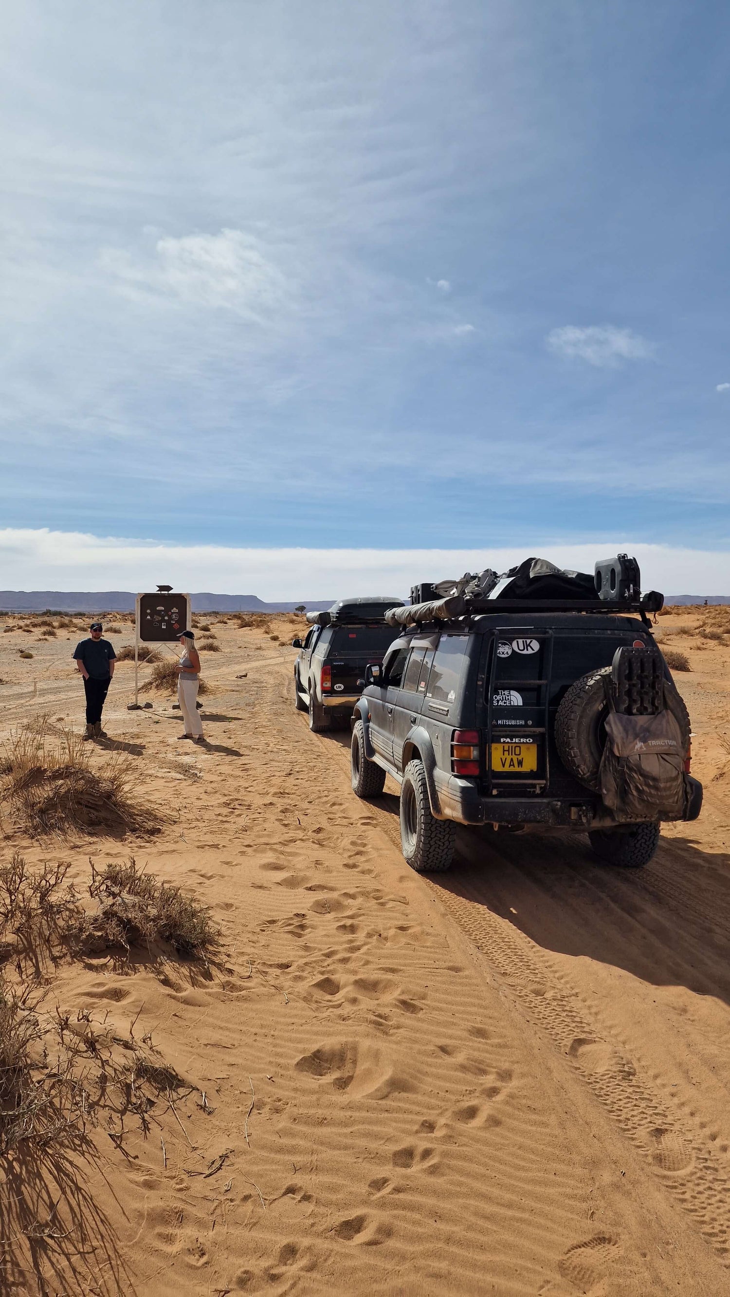 Photo of 2 overland expedition pickup trucks in the Moroccan desert.