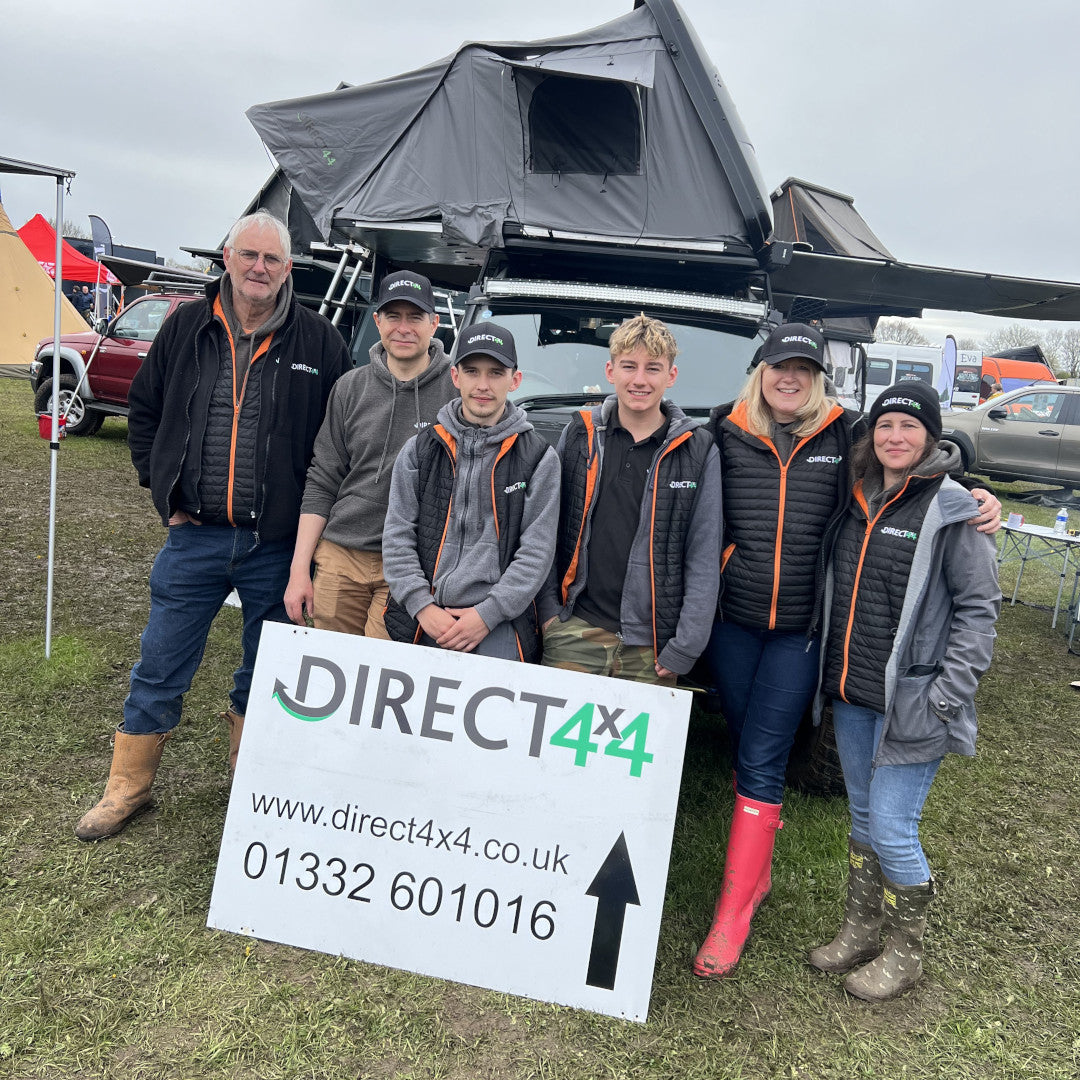 Photo of the Direct4x4 team stood in front of a Land Rover Defender in a field.