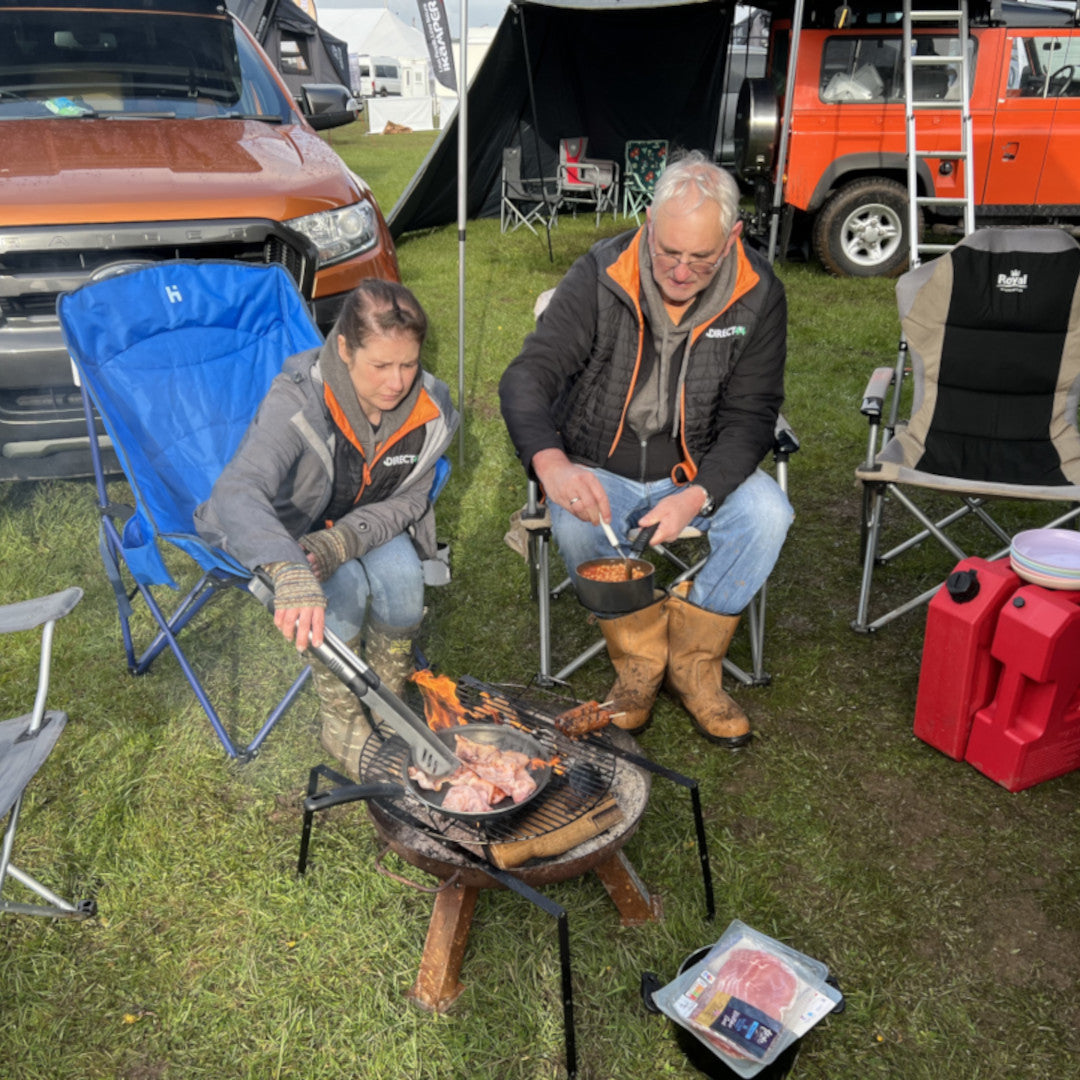 Photo of 2 people campsite cooking.