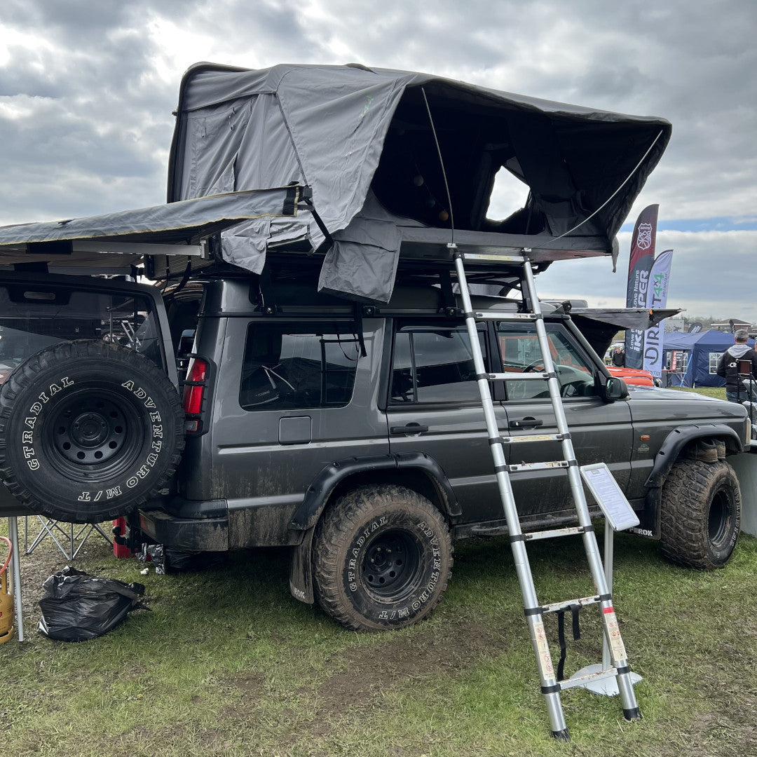 A photo of the dark grey Land Rover Discovery 2 from Direct4x4, kitted out with lots of overland expedition camping gear.
