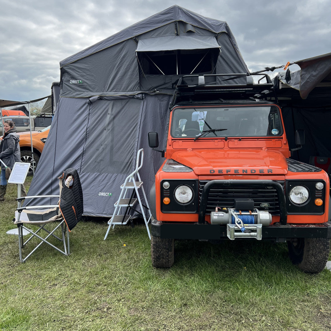 A photo of the bright orange Land Rover Defender 90 from Direct4x4, kitted out with lots of overland expedition camping gear.