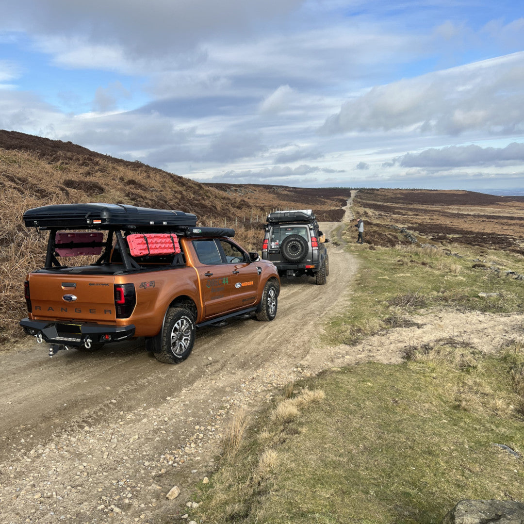 Photo of a Ford Ranger Wildtrak and a Land Rover Discovery offroad green laning in the peak districts on a dusty track.