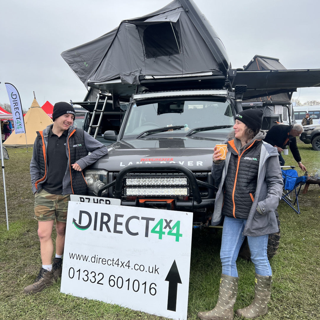 Photo of a man and a woman in front of a Land Rover Discovery 4x4 equipped with lots of Direct4x4 expedition camping gear.
