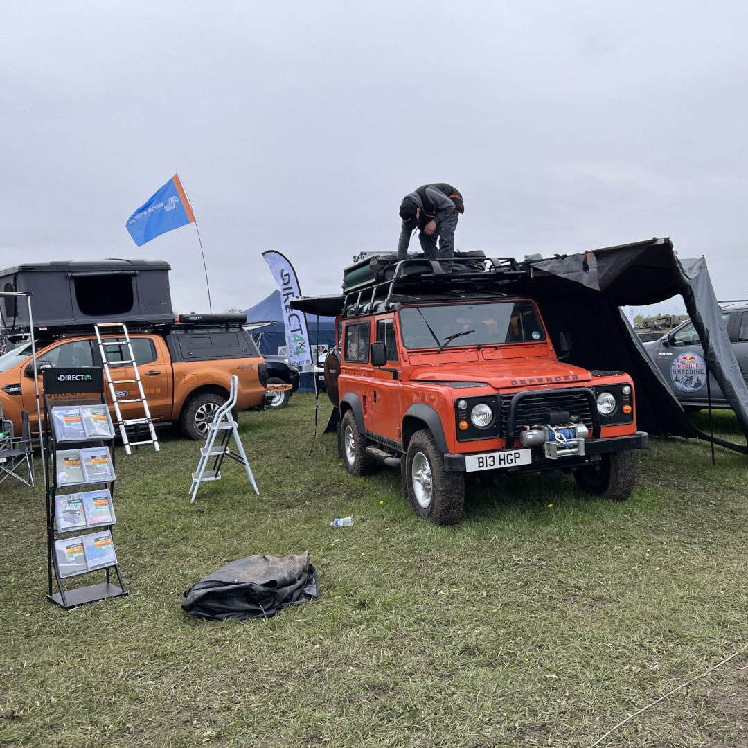 A photo of the bright orange Land Rover Defender 90 from Direct4x4, kitted out with lots of overland expedition camping gear.